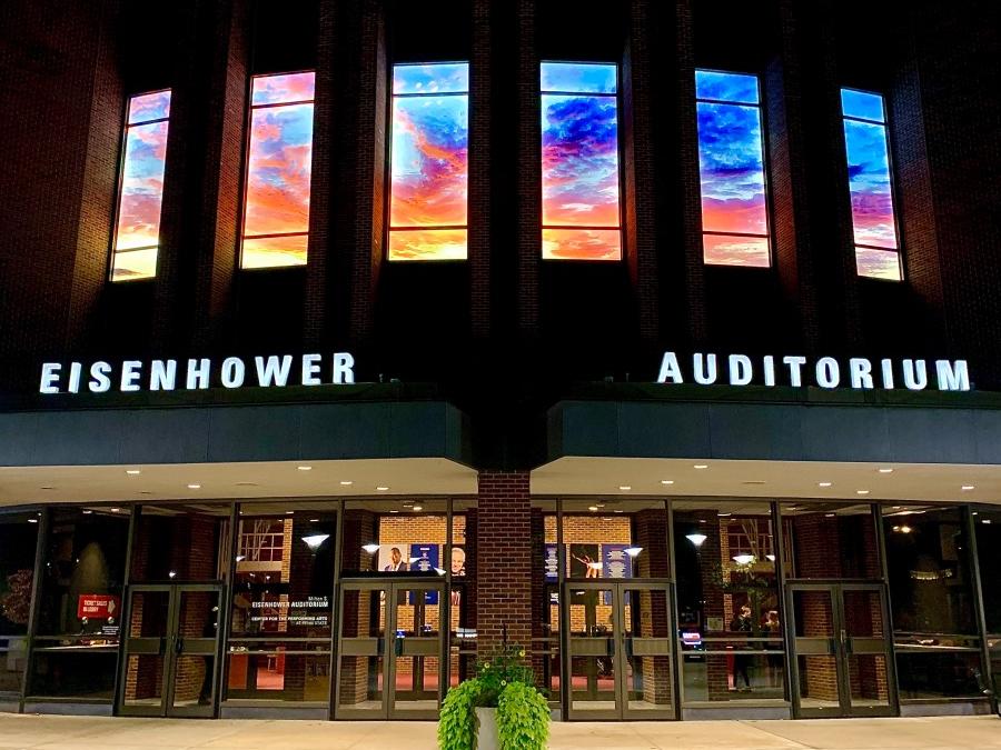 Imagery of a sunset is shown in the long, vertical windows of Eisenhower Auditorium.